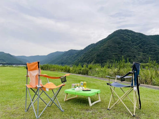 草原に置かれた2脚のアウトドアチェアとテーブル